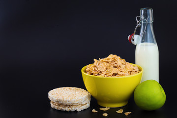 Energy breakfast for diet cereal flakes of corn milk and green apple on black background with copy space