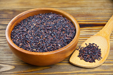 Raw black rice in bowl on  wooden background
