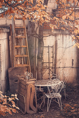 Old forgotten garden with rustic chairs and tables