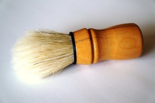 wooden shaving brush laying on a plain background