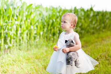 Funny baby girl is playng in the field of corns at christening
