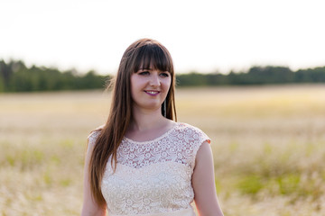 Fototapeta na wymiar Beautiful young woman wearing elegant white dress standing on a white field