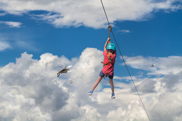 Boy riding on a zip line above the clouds