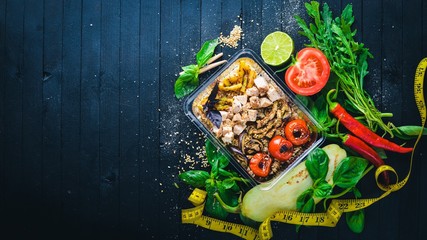 Risotto Rice with meat and grilled vegetables. Healthy Diet Food. Lunch Boxing. On a black wooden background. Top view. Free space for text.