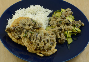 Chicken and rice with mushroom gravy and sliced zucchini dinner on blue plate