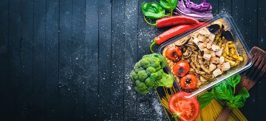 Risotto Rice with meat and grilled vegetables. Healthy Diet Food. Lunch Boxing. On a black wooden background. Top view. Free space for text.