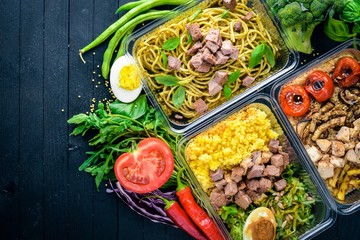 Pasta and buckwheat with meat and fresh vegetables. Healthy Diet Food. Lunch Boxing. On a black wooden background. Top view. Free space for text.