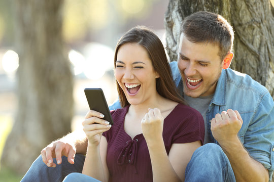 Excited couple reading news in a phone