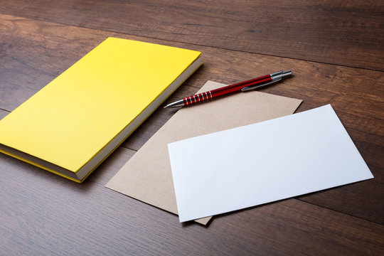 The brown envelope with yellow diary and pen on wooden background.