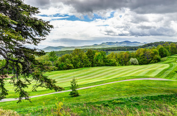 Fototapeta na wymiar Landscape view of green golf course with hills in summer in La Malbaie, Quebec, Canada in Charlevoix region