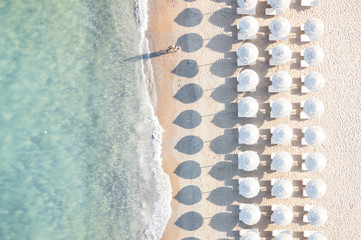 Aerial view of white beach, umbrellas and turquoise clear water during sunset, Mediterranean sea, Sardinia, Italy,