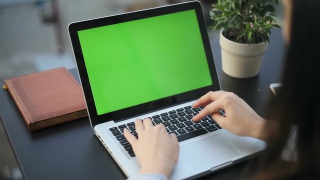 Closeup woman sitting table notebook female hands keyboarding laptop using texting pointing networking green screen chroma key chromakey keyboard white device working message student businesswoman