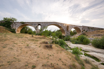 Fototapeta na wymiar Pont Julien - circa 2000 years old Roman stone arch bridge over the Calavon river, Provence, France
