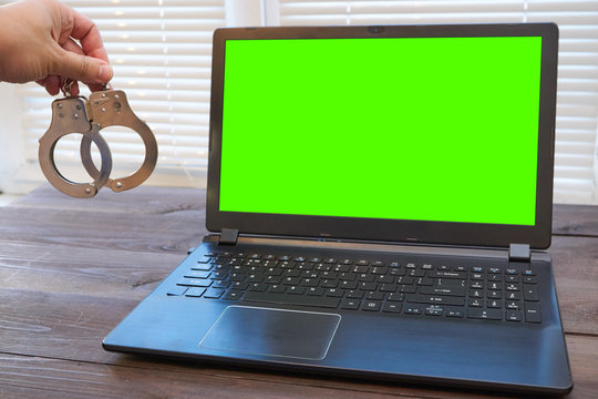 man holding handcuffs near laptop