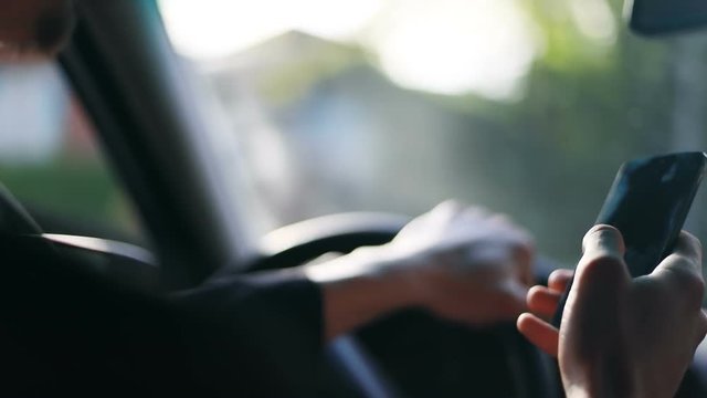 Closeup man driving car hand hands holding using phone mobile black tapping touching screen touchscreen busy businessman checking texting message traffic driver connection device display automobile