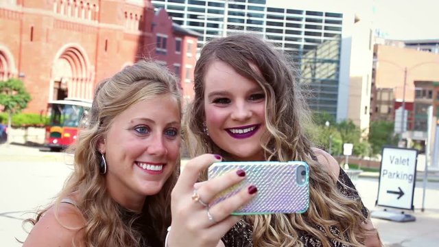 Two Dressed up Female Millennials taking selfies in downtown metropolitan urban area V2