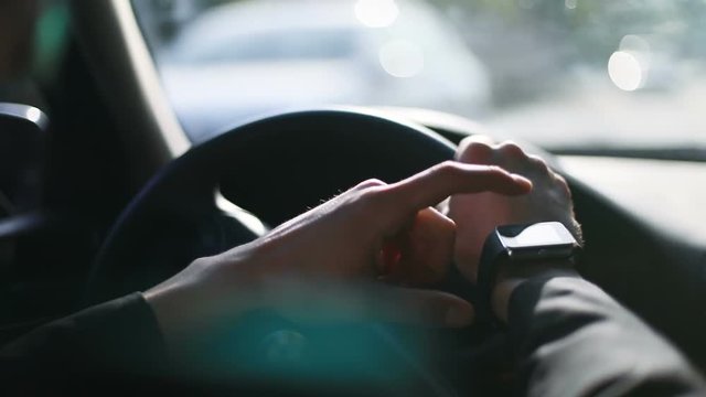 Close up man using smartwatch application checking time notification destination wrist hands hand driving car blurred road wearable wristwatch smart watch busy tapping screen touching display hurrying