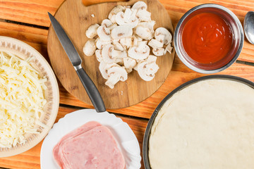 Flat lay preparing pizza with mushrooms ketchup ham cheese on the wooden table