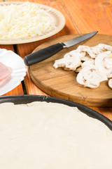 Pizza dough with pizza ingredients mushrooms sliced ham cheese