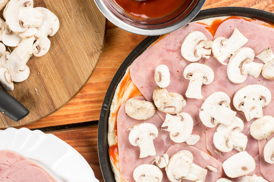 Flat lay above table with pizza ingredients, mushrooms ham ketchup