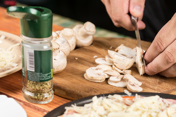 Slicing fresh raw mushrooms for baking pizza