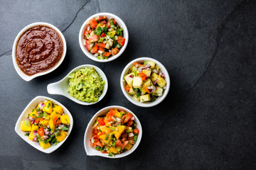 Traditional famous mexican sauces chocolate chili mole poblano, pico de gallo, avocado guacamole, salsa bandera, pinapple salsa, mango salsa on slate gray background