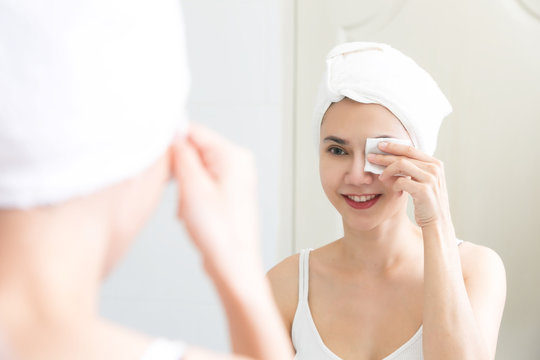Healthy fresh girl removing makeup from her face with cotton pad. Skin care and beauty concept.