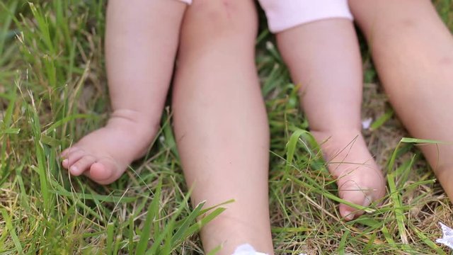 Close-up of legs of two young children, a newborn and 5 years on the grass in the Park.