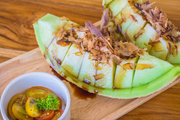 Melon with tomato salad menu..Fresh sweet melons sliced on wooden table.
