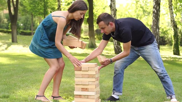 Young boy and girl building a tower from wooden blocks playing a game of jenga in the Park.