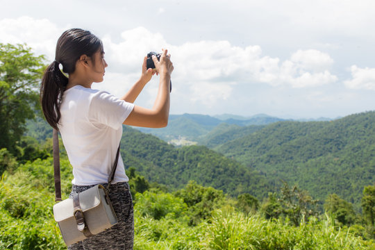 Woman hiker taking photo with camera at mountain