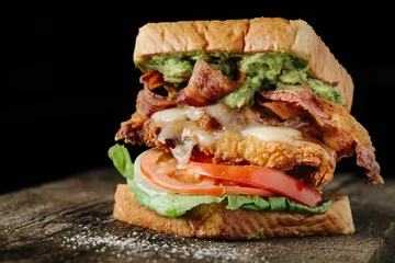 Selbstklebende Fototapeten Hühnchen und Avocado BLT-Sandwich auf schwarzem Hintergrund © tisaeff