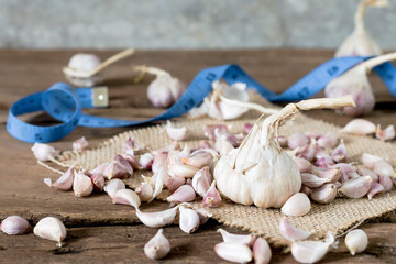 a Big garlic among seed garlic and measuing tape on old wooden table with big garlic background