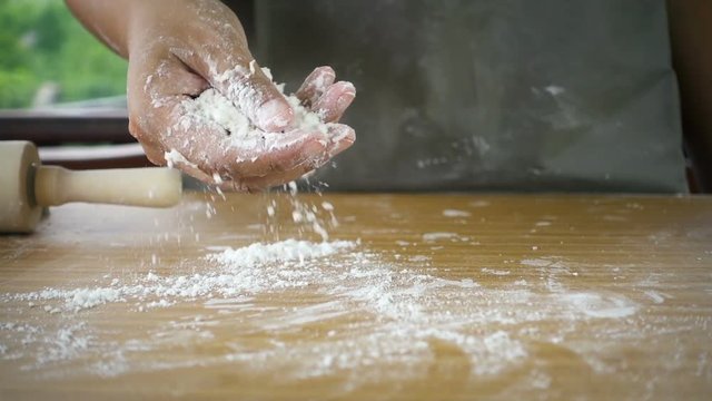 Female hand throwing flour on the table, slow motion