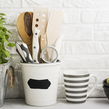 Kitchen still life on a white brick wall background: various cutting boards, tools, greens for cooking, fresh vegetables. Selective focus.