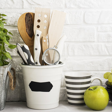 Kitchen still life on a white brick wall background: various cutting boards, tools, greens for cooking, fresh vegetables. Selective focus.