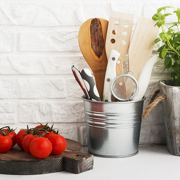 Kitchen still life on a white brick wall background: various cutting boards, tools, greens for cooking, fresh vegetables. Selective focus.