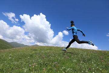 young fitness woman runner running jumping on grassland