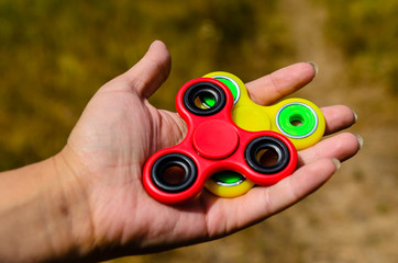Red and yellow fidget spinners in female hand