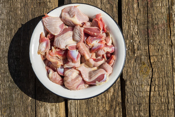 Raw chicken gizzards in metal enamelled bowl on rustic wooden table