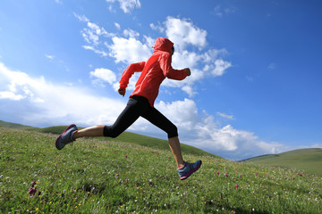 young fitness woman runner running on grassland