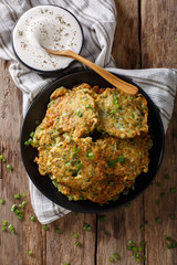 Homemade zucchini fritters with greens and sour cream close-up. Vertical top view