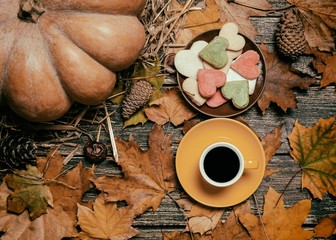 Cup of coffee and heart shape cookies on autumn background.
