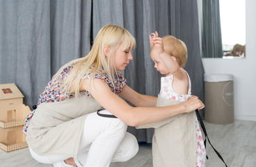 Mother dressing her daughter in the morning for the help with a household