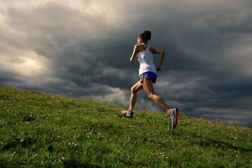 young fitness woman runner running on grassland