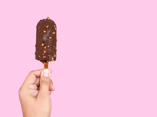 Hand holding chocolate ice cream on pink