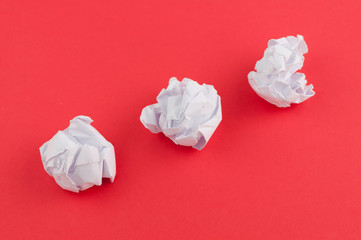 Three white crumpled papers on red paper background
