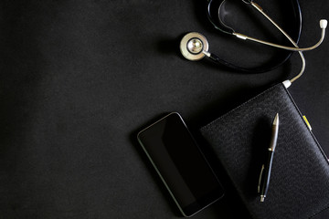 Dark leather modern doctor desk table with stethoscope and supplies.