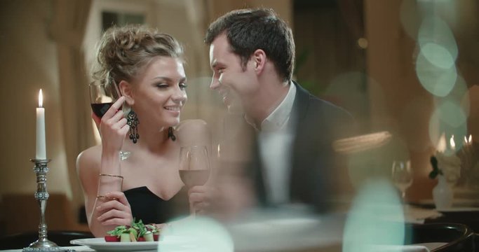 young couple with a glass of wine in the restaurant , flirting on a date