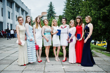 Faulous young women graduates in chic evening gowns posing outside in the park. - obrazy, fototapety, plakaty
